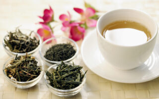 Tasse grüner Tee auf Tisch und vier Schalen grüner Tee